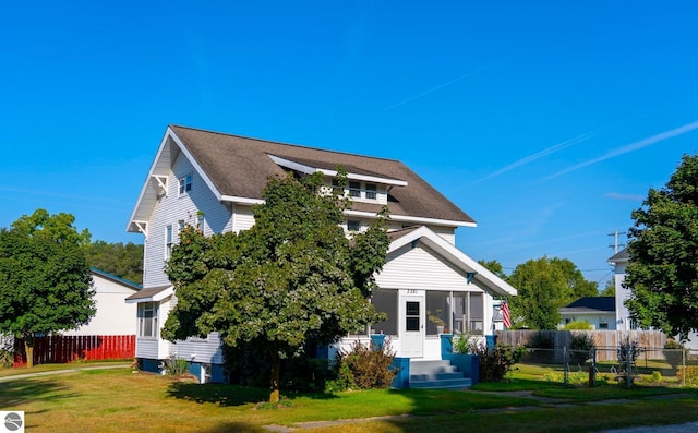 back of property featuring a lawn and fence