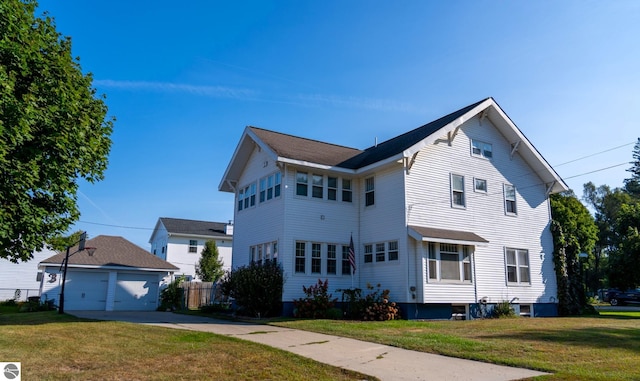 view of front of house with a garage, a front yard, and an outbuilding