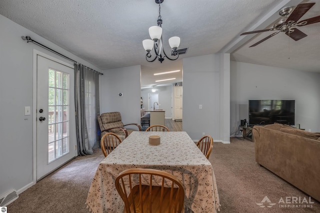 dining space with ceiling fan with notable chandelier, carpet, lofted ceiling with beams, and a textured ceiling