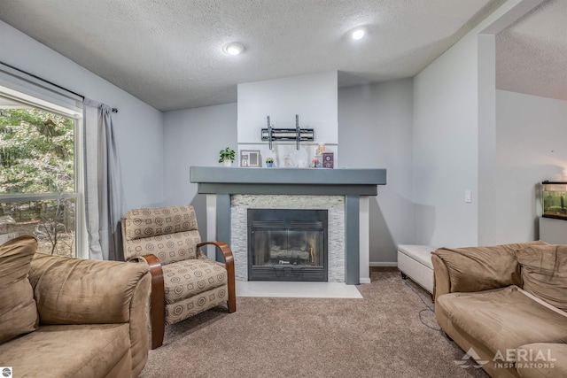 living room featuring a textured ceiling, carpet flooring, and a stone fireplace