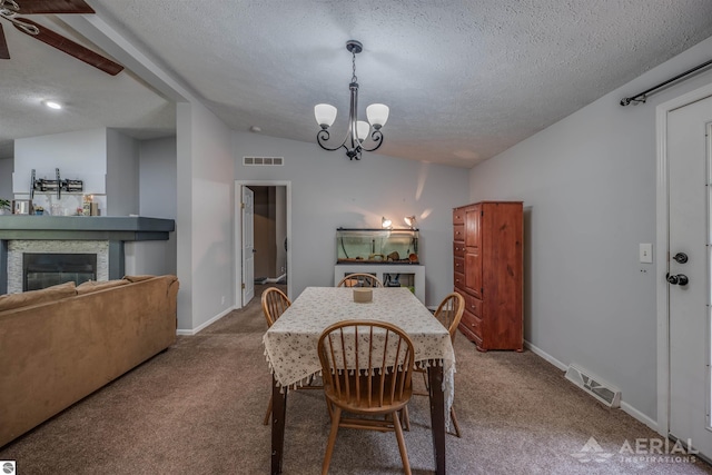 carpeted dining space with a textured ceiling, lofted ceiling, ceiling fan with notable chandelier, and a fireplace