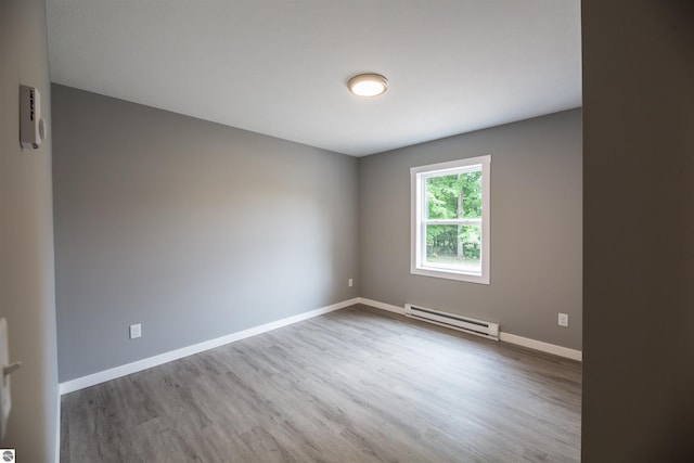 empty room featuring a baseboard heating unit and hardwood / wood-style floors