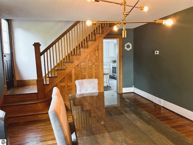 staircase featuring hardwood / wood-style floors, an inviting chandelier, and a textured ceiling