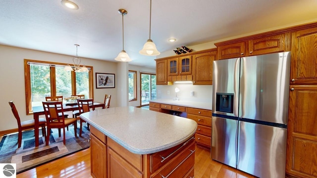 kitchen with stainless steel refrigerator with ice dispenser, a center island, light hardwood / wood-style floors, and a wealth of natural light