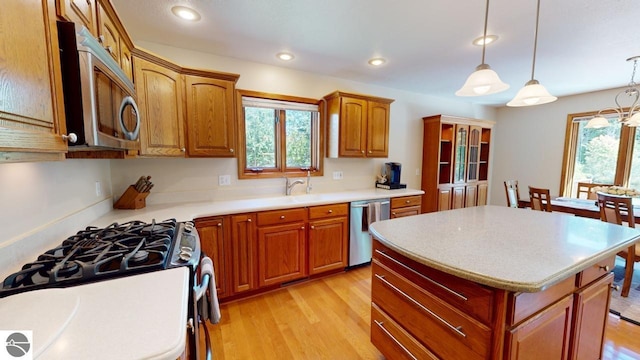 kitchen featuring stainless steel appliances, a wealth of natural light, a center island, and decorative light fixtures