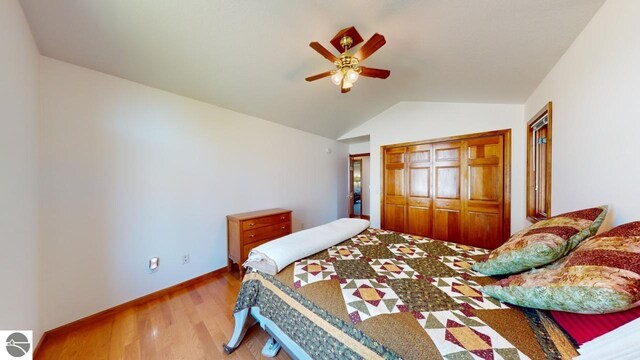 bedroom with wood-type flooring, lofted ceiling, ceiling fan, and a closet