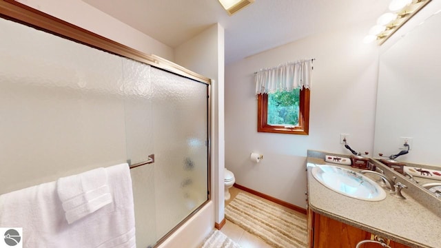 full bathroom featuring tile patterned floors, shower / bath combination with glass door, vanity, and toilet