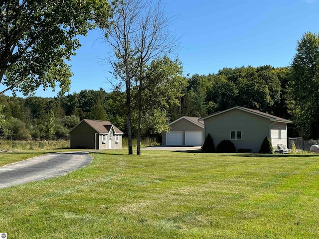 ranch-style home with a front yard, a garage, and an outbuilding