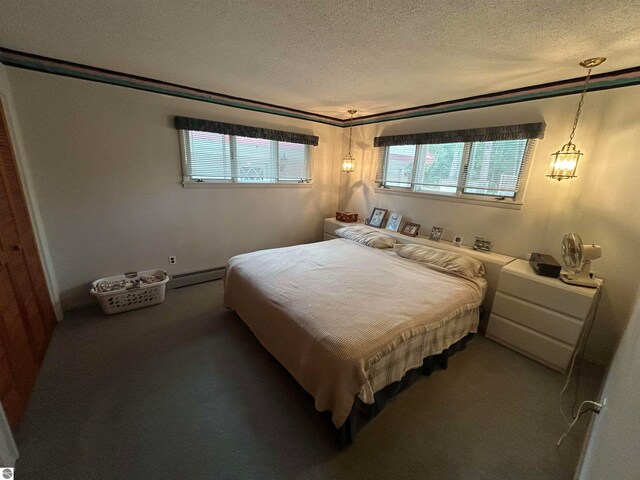 carpeted bedroom with baseboard heating and a textured ceiling