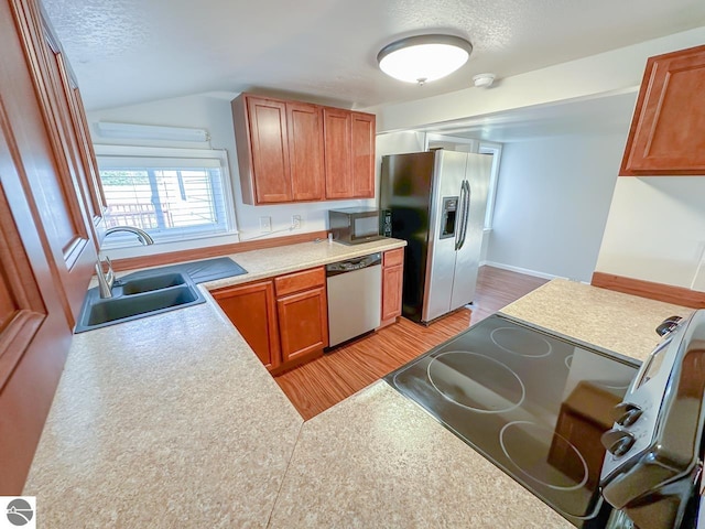 kitchen featuring a textured ceiling, light hardwood / wood-style flooring, stainless steel appliances, and sink