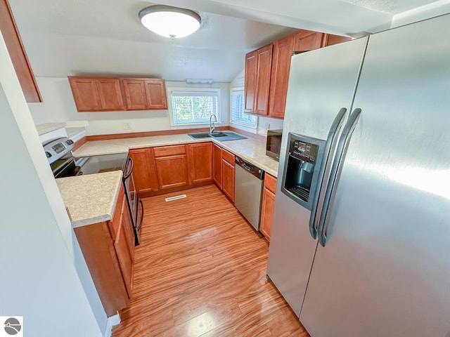 kitchen featuring stainless steel appliances, sink, and light hardwood / wood-style floors