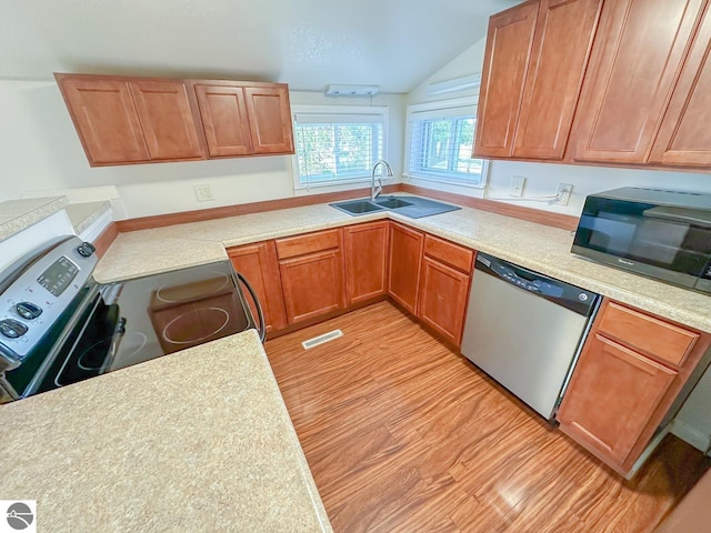 kitchen with vaulted ceiling, sink, appliances with stainless steel finishes, and light hardwood / wood-style floors