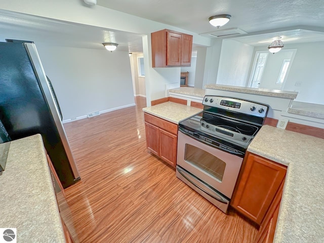 kitchen featuring a textured ceiling, light hardwood / wood-style flooring, and appliances with stainless steel finishes