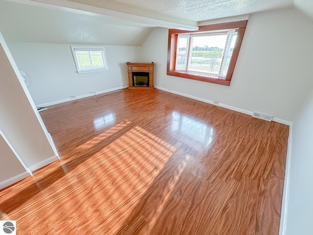 interior space with vaulted ceiling, a textured ceiling, and light hardwood / wood-style flooring