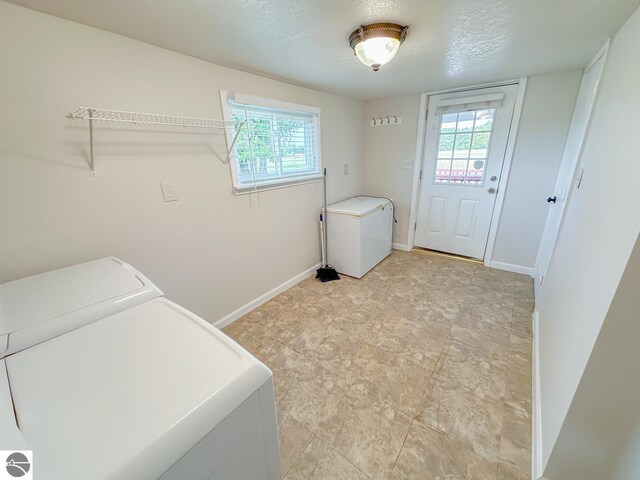 laundry room featuring a wealth of natural light, independent washer and dryer, and a textured ceiling