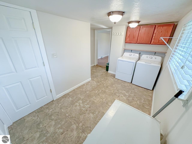 clothes washing area with a textured ceiling, cabinets, and washing machine and dryer