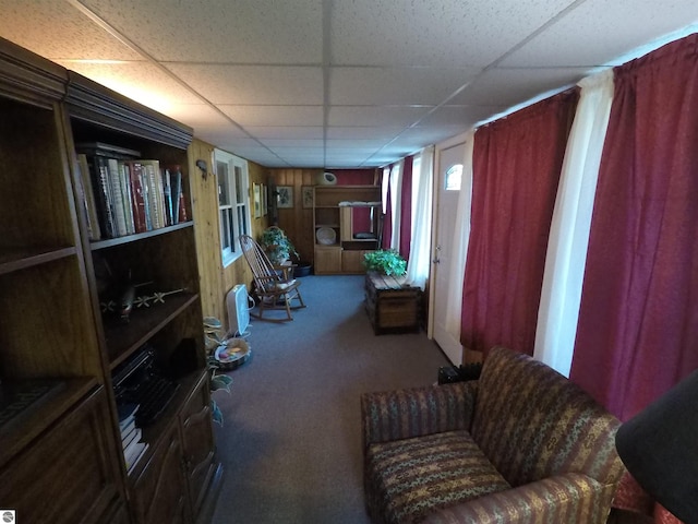 living area featuring a paneled ceiling and carpet flooring