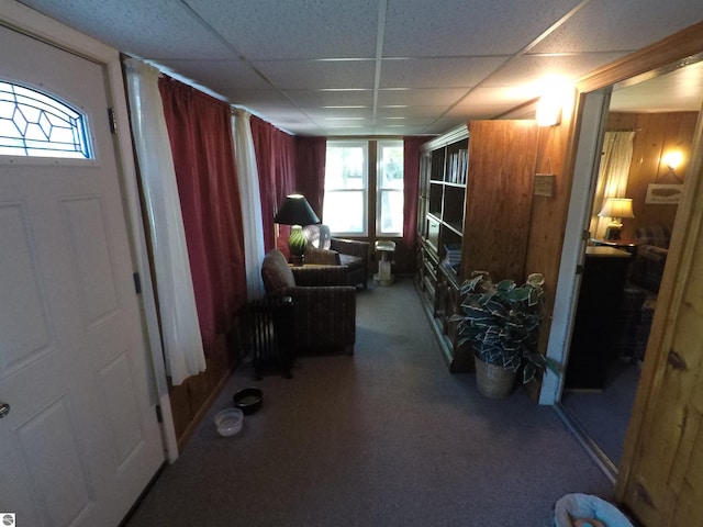 interior space with a paneled ceiling, wooden walls, and carpet floors