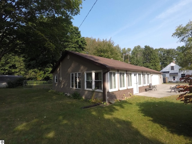 view of side of home featuring a patio area, a garage, and a lawn