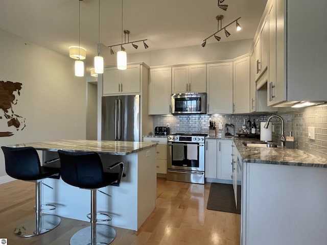 kitchen featuring white cabinets, appliances with stainless steel finishes, a center island, and sink