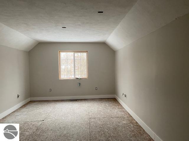 additional living space with a textured ceiling and lofted ceiling