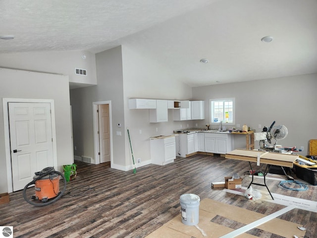 kitchen featuring a textured ceiling, dark wood-type flooring, sink, high vaulted ceiling, and white cabinets