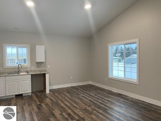 kitchen featuring light stone countertops, dark wood-type flooring, sink, white cabinets, and lofted ceiling