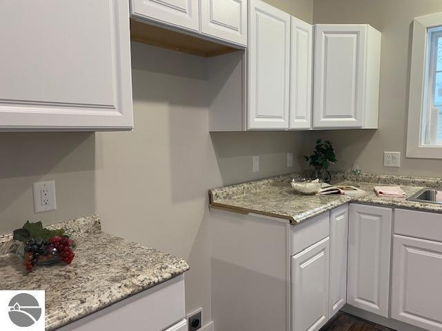 kitchen featuring light stone countertops and white cabinets