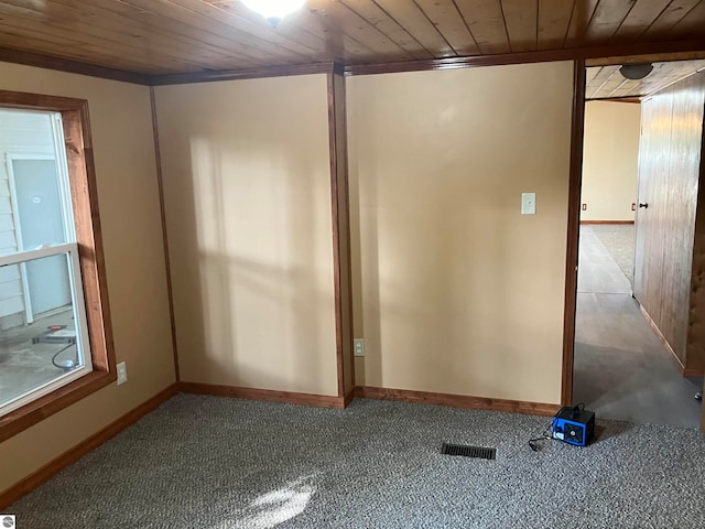 carpeted spare room featuring wood ceiling