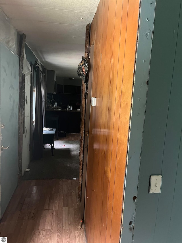 hallway featuring wood-type flooring and wooden walls