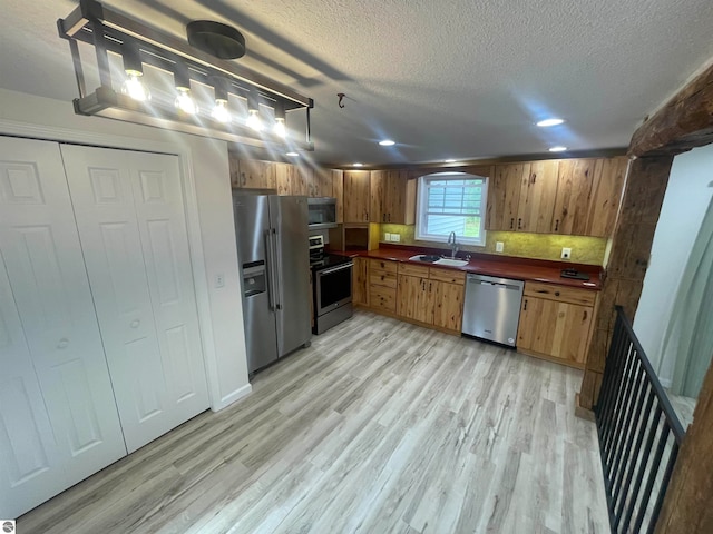 kitchen featuring light hardwood / wood-style flooring, stainless steel appliances, a textured ceiling, and sink