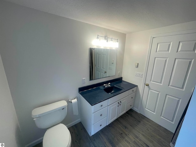 bathroom featuring wood-type flooring, a textured ceiling, vanity, and toilet