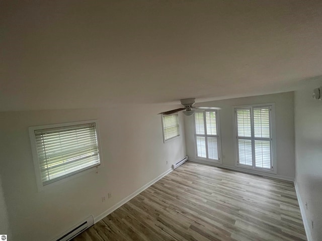 unfurnished room with ceiling fan, baseboard heating, light wood-type flooring, and lofted ceiling