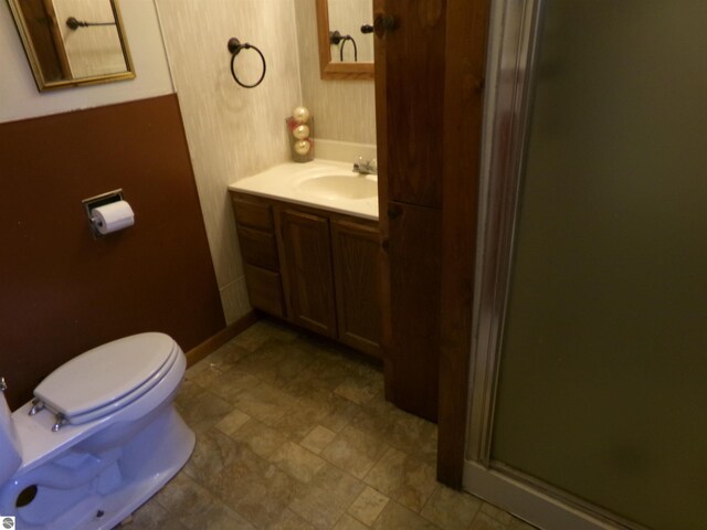 bathroom with vanity, toilet, and a shower with door