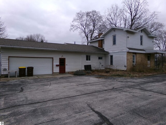 back of property featuring a garage and cooling unit