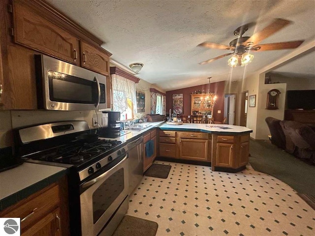 kitchen with appliances with stainless steel finishes, ceiling fan with notable chandelier, kitchen peninsula, a textured ceiling, and lofted ceiling