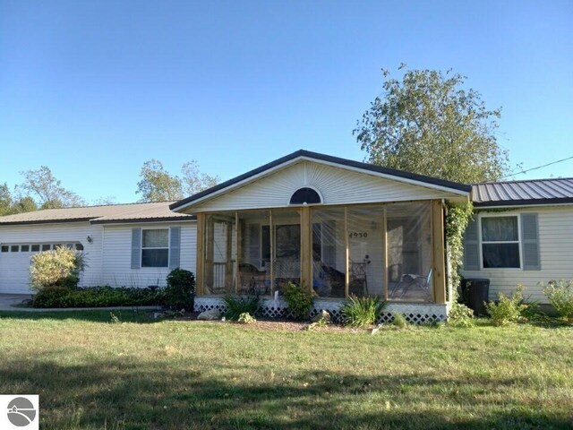 single story home featuring a garage, a front lawn, and a sunroom