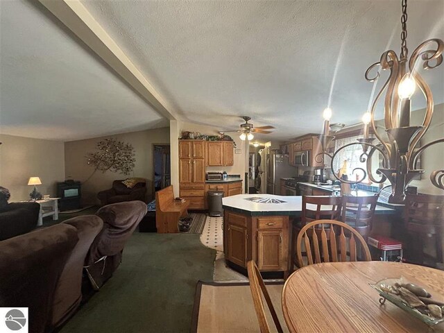 kitchen featuring stainless steel appliances, a textured ceiling, a center island, ceiling fan, and vaulted ceiling with beams