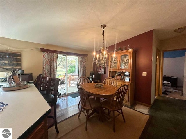 dining room featuring light colored carpet, a notable chandelier, and a textured ceiling