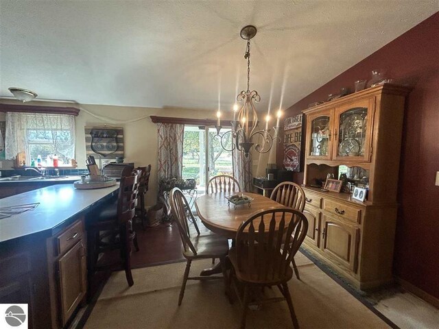 carpeted dining room featuring an inviting chandelier, lofted ceiling, a textured ceiling, and sink