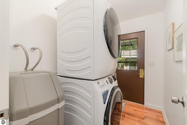 washroom with hardwood / wood-style floors and stacked washer and clothes dryer