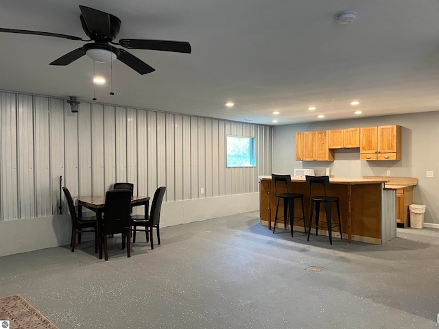 dining space featuring ceiling fan and bar