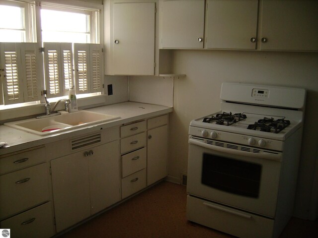 413 N Fancher St, Mount Pleasant, MI 48858 - kitchen featuring white cabinetry, light countertops, white range with gas stovetop, and a sink