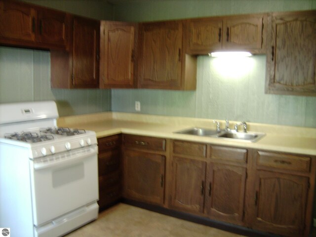 413 N Fancher St, Mount Pleasant, MI 48858 - kitchen with a sink, brown cabinets, white gas range, and light countertops