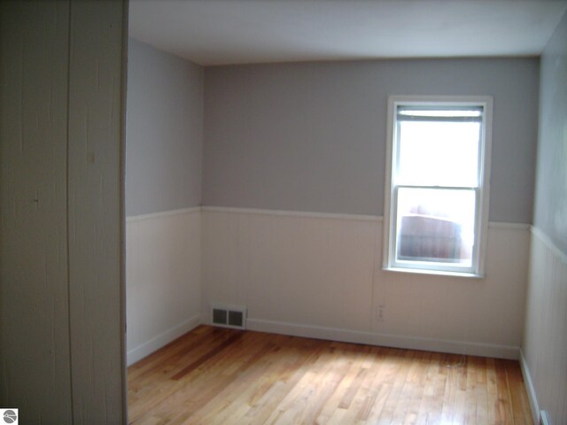 413 N Fancher St, Mount Pleasant, MI 48858 - unfurnished room featuring visible vents, wainscoting, and light wood-style floors