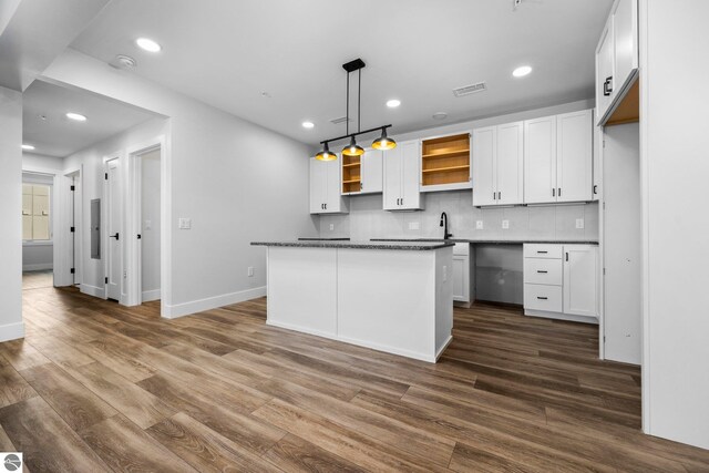 kitchen with hanging light fixtures, decorative backsplash, white cabinets, a kitchen island, and dark hardwood / wood-style flooring