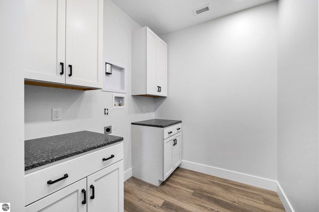 kitchen with dark stone countertops, light hardwood / wood-style flooring, and white cabinets