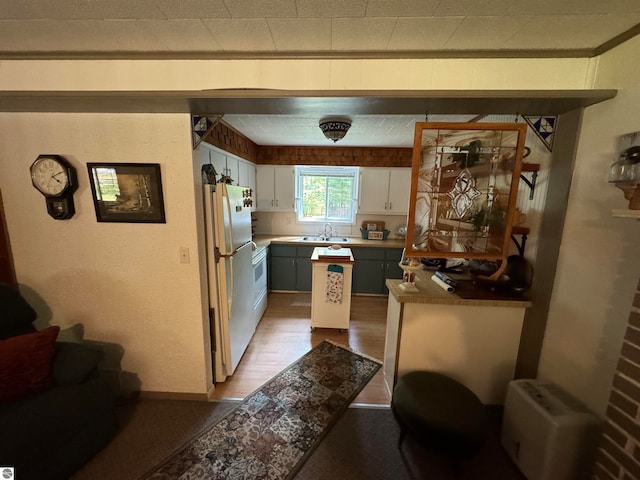 kitchen with gray cabinets, hardwood / wood-style flooring, sink, white cabinets, and white fridge