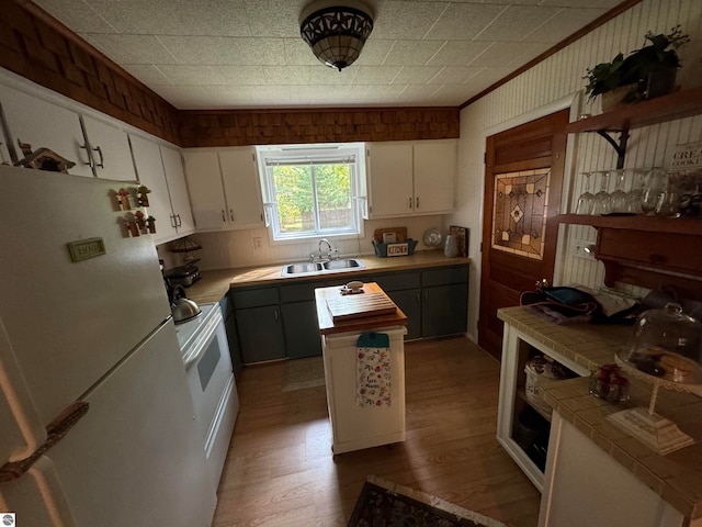 kitchen featuring hardwood / wood-style flooring, sink, white cabinetry, stove, and white fridge