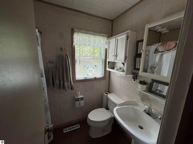 bathroom with tile walls, curtained shower, tasteful backsplash, toilet, and sink